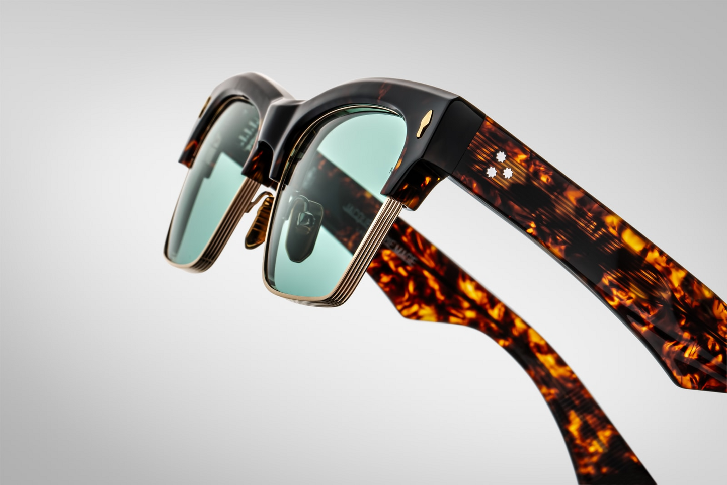 Close-up of Bugsy Beau temple—Havana cured cellulose acetate over hidden wirecore, light‑gold arrowhead front pin detail, tension‑secured 7‑barrel hairline hinge, and logo‑engraved nose pad.