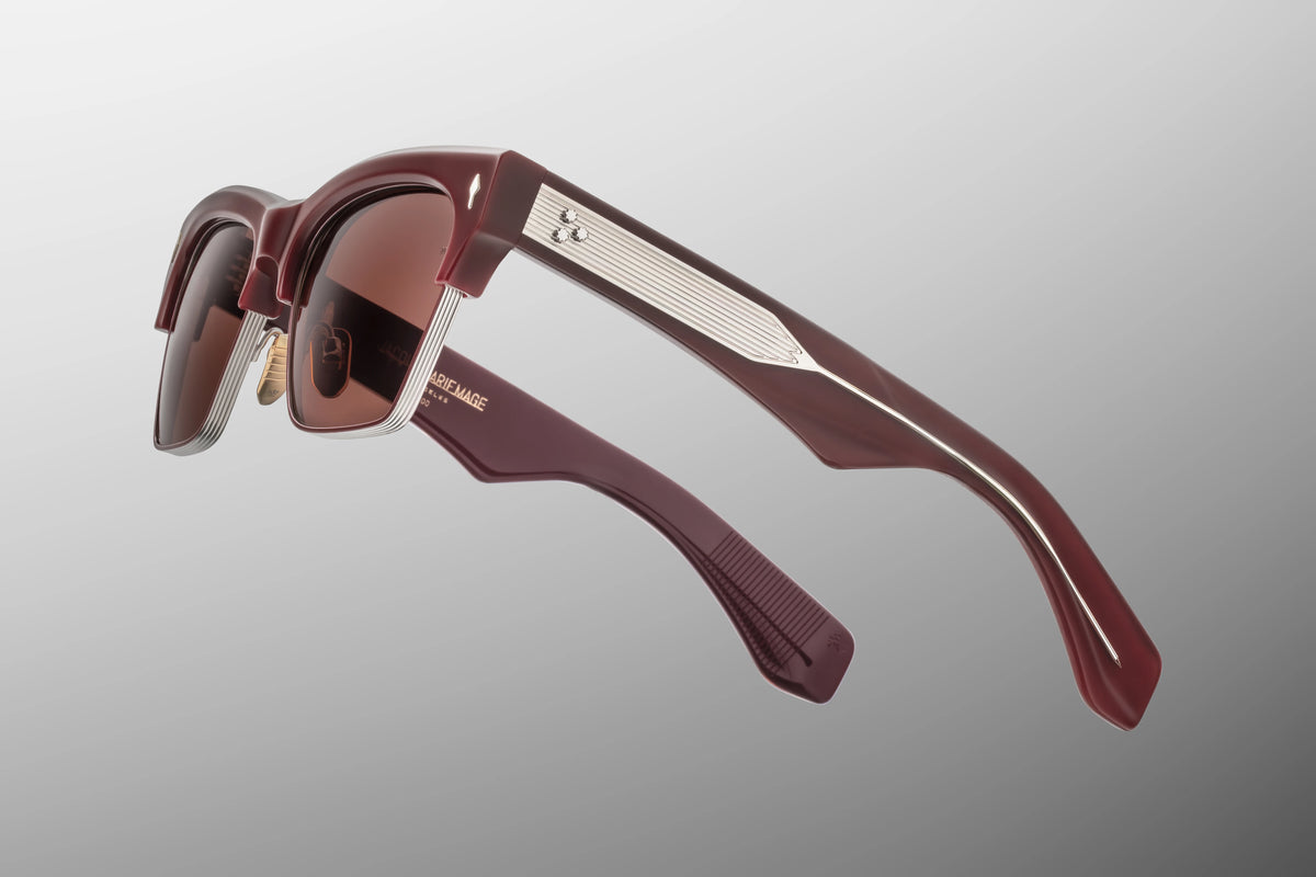 Macro shot of the temple arm on Jacques Marie Mage Bugsy Bordeaux Empire sunglasses. The transparent exterior laminate acts as a window to display a polished silver palladium classic wire core etched with intricate filigree.