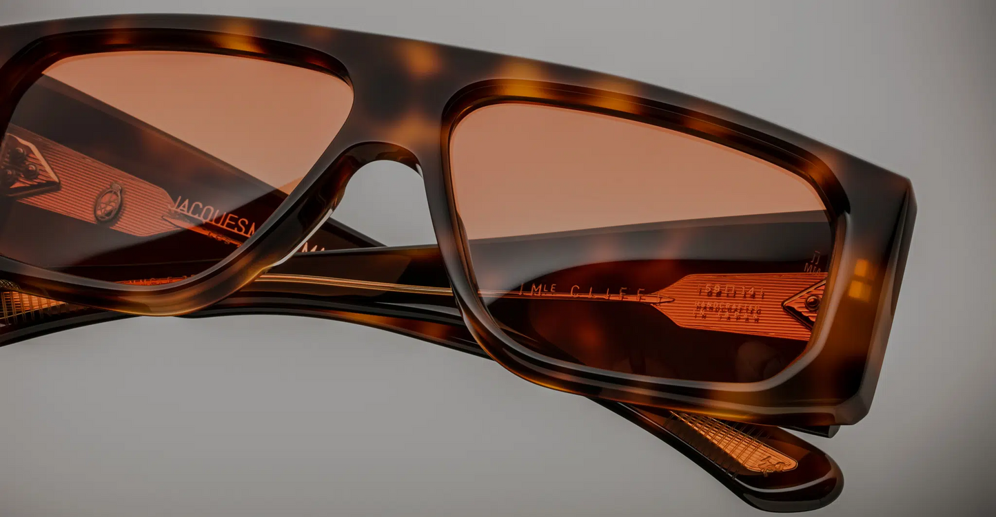 Close-up of the lenses of Jacques Marie Mage Cliff Havana 7 sunglasses, showing the dark, high-quality lenses with a slight gradient. The lenses are set within a bold, square-shaped frame made of rich Havana acetate. The fine craftsmanship is evident in the clean, sharp edges of the frame around the lenses, enhancing the sophisticated and luxury appeal of the sunglasses