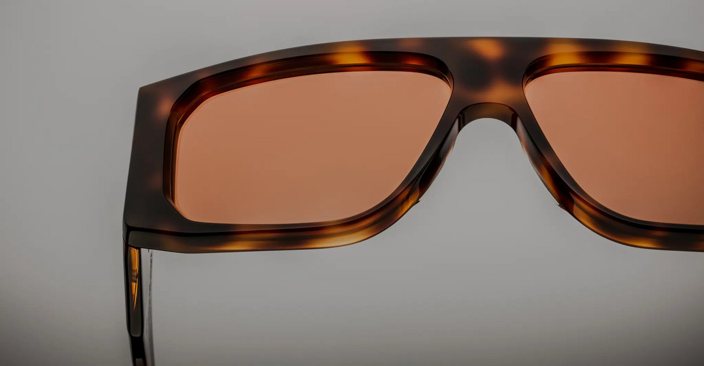 Close-up of the lenses of Jacques Marie Mage Cliff Havana 7 sunglasses, showing the dark, high-quality lenses with a slight gradient. The lenses are set within a bold, square-shaped frame made of rich Havana acetate. The fine craftsmanship is evident in the clean, sharp edges of the frame around the lenses, enhancing the sophisticated and luxury appeal of the sunglasses