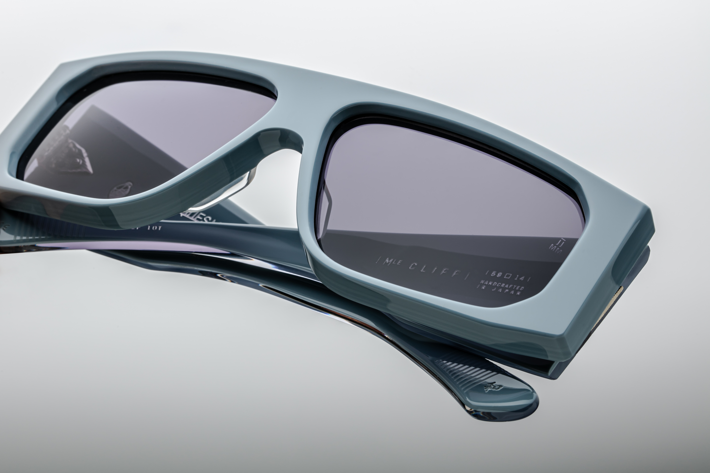 Close-up of the lenses of Jacques Marie Mage Cliff Tiger sunglasses, showcasing the dark lenses with a slight gradient. The rich, marbled Tiger acetate frame surrounds the lenses, with its unique pattern adding depth and texture to the overall design. The quality of both the frame and lenses reflects the premium craftsmanship of the sunglasses