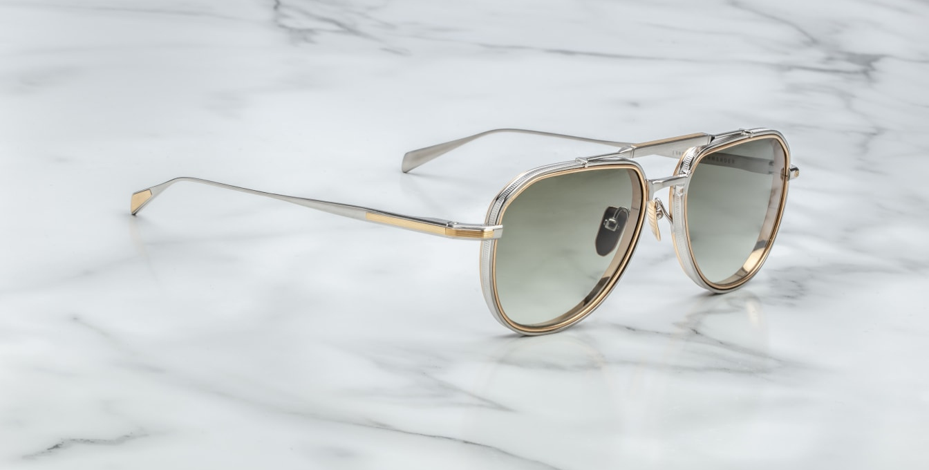 Side profile of Jacques Marie Mage Commander sunglasses in Silver, featuring a dual-tone silver and gold beta titanium frame with 6mm titanium lens-rim inserts. The design includes a double nose bridge, hairline-engraved temples with wing tips, and custom nose pads. Handcrafted in Japan with a limited production of 500 pieces, offering 100% UV protection with light bottle green CR39 lenses.