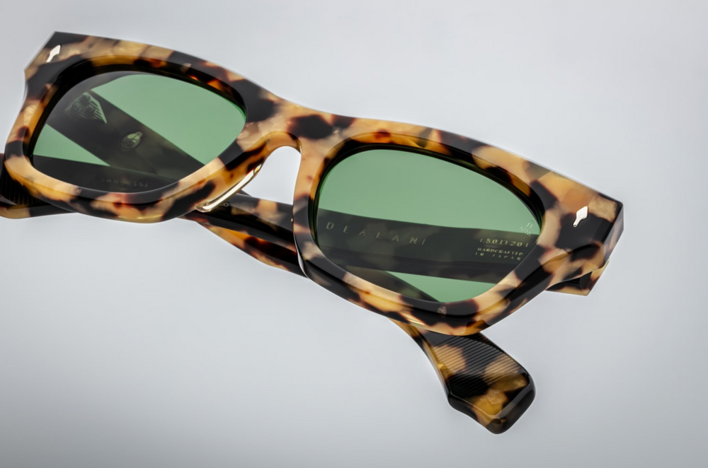Jacques Marie Mage Dealan Gold Dust sunglasses featuring bold, square 10 mm cured acetate frames in a speckled honey‑and‑caramel ‘Gold Dust’ pattern. Sterling‑silver arrowhead front pins and spur‑shaped rivets accent the temples, which house hidden silver wire‑core reinforcements and custom 7‑barrel hairline hinges. The demo lenses are Highland‑green CR39 with backside anti‑reflective coating, offering full UV protection. Handcrafted in Japan limited‑edition release, inspired by vintage Japanese acetate