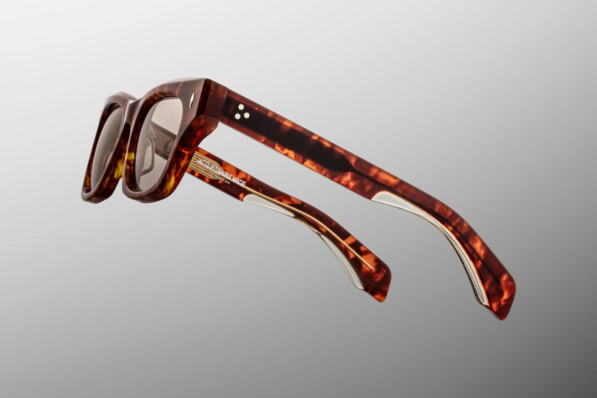 Focused close-up of the 142mm temple arms of the Dealan 50/20 Honeycomb glasses. The image emphasizes the custom-engraved, light gold inner wirecore running through the core of the temple, visibly shimmering through the translucent amber sections of the double-laminated Havana acetate arm.