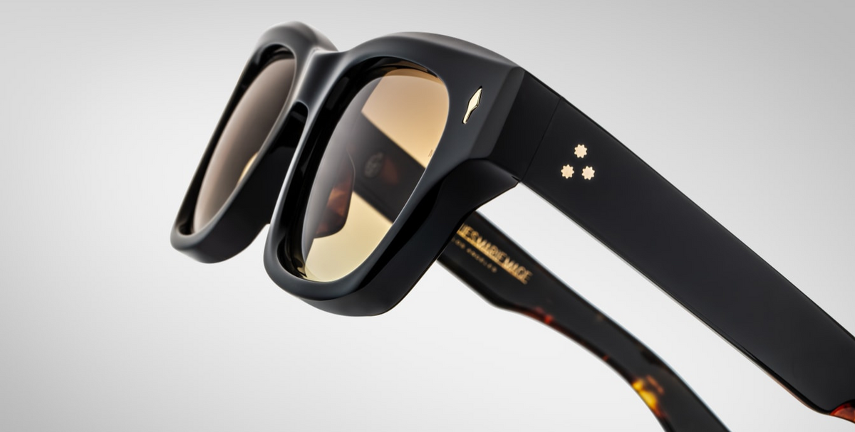 Close-up of the temples of Jacques Marie Mage Dealan 53 Noir 15 sunglasses, focusing on the glossy black acetate finish. Gold-tone metal accents at the temple ends add a polished touch, highlighting the brand's signature craftsmanship. The temples taper elegantly, contributing to the sunglasses' refined look
