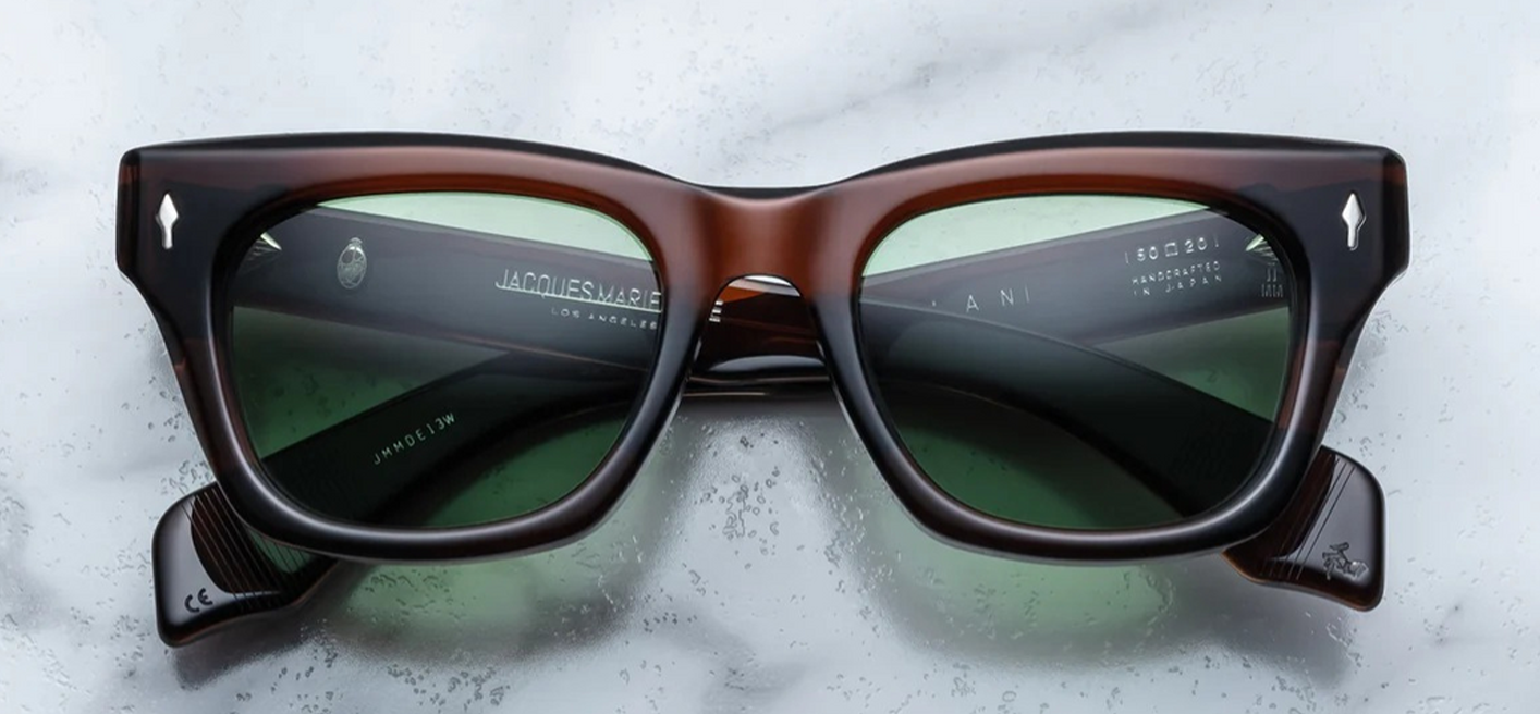 Jacques Marie Mage Dealan sunglasses in Zoltar, featuring a bold square frame with subtle cat-eye shaping. Crafted from 10mm brown tortoise cured cellulose acetate, the frame showcases sterling silver arrowhead front pins and a distinctive double-bridge design. The green CR39 lenses offer 100% UV protection and backside anti-reflective treatment