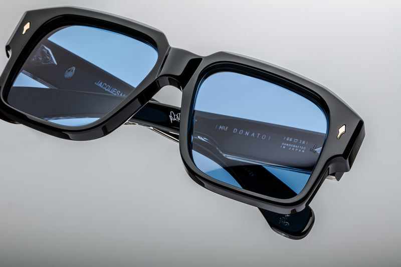 Close-up of the lenses of Jacques Marie Mage Donato Shadow sunglasses, showcasing the dark gradient lenses set within the sleek Shadow acetate frame. The clean, sharp lines around the lenses highlight the minimalist design, while the engraved signature symbol on the temple tip adds an extra layer of elegance and exclusivity
