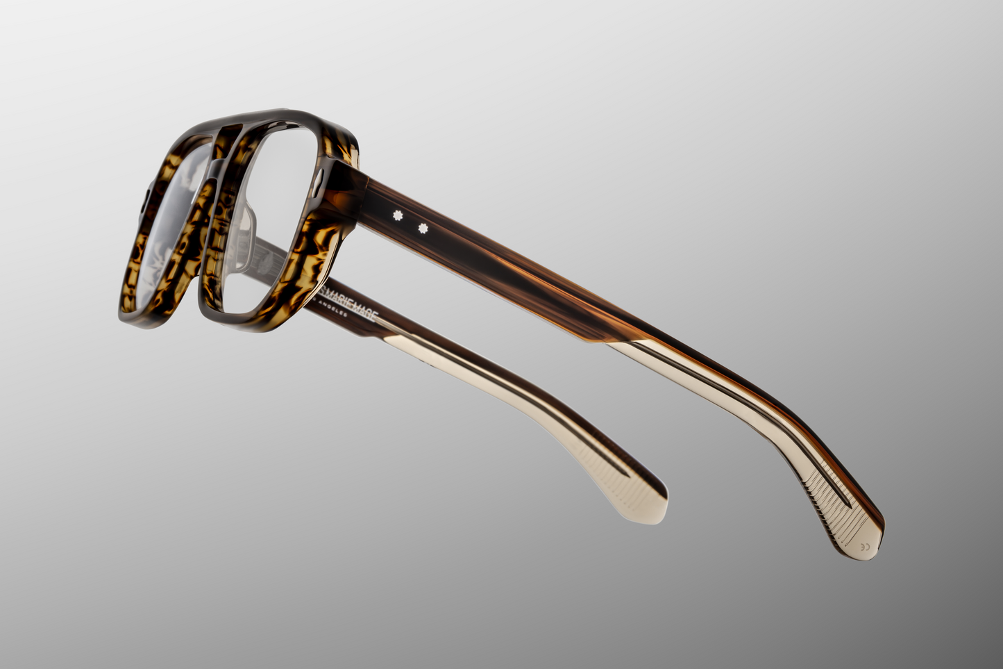 Side profile of Evans Hazel showing custom double‑laminated acetate temples, hidden wirecore, sterling silver tension‑secured 7‑barrel hinge with spur‑shaped rivets, and 3D metal cameo logo