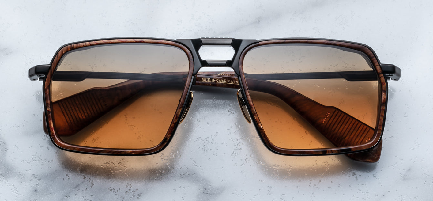 Front‑facing view of Jacques Marie Mage GT‑R sunglasses in the Boa colourway: large, square navigator‑style lenses with Boa brown triple gradient tint. The full titanium frame has a double bridge; the upper bridge is solid metal and below it is a second slim bar. Acetate rim inserts in black trimmed bezel surround each lens. Nose pads visible, dark temple arms resting behind