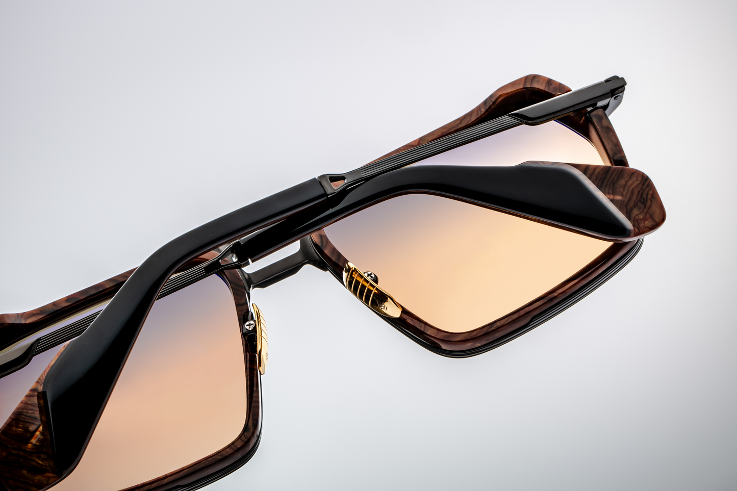 View from below or slightly under the sunglasses: underside of the nose bridge, inside of the rims showing black acetate insert from below. The frame’s inner surfaces are smooth, hardware on nose pads visible; lens gradient lighter from the bottom edge, showing subtle tinting