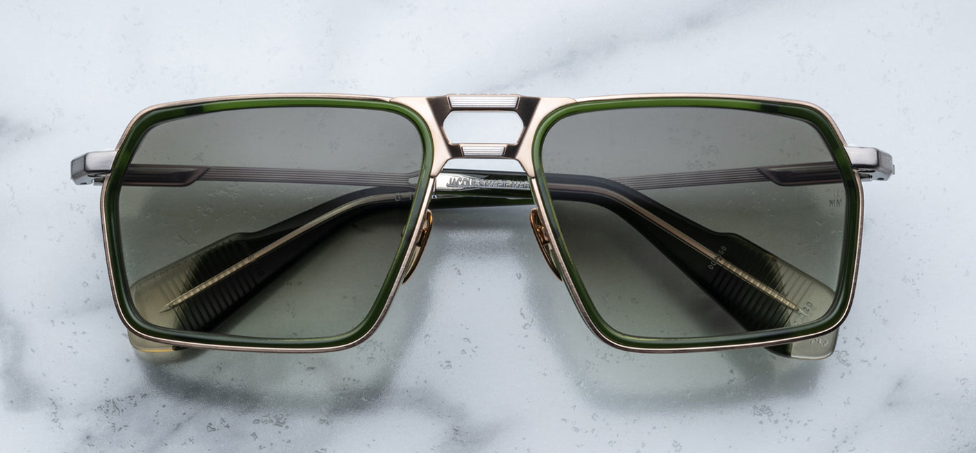 Jacques Marie Mage GT‑R “Rover”: front‑facing view showing full frame and lenses. Light gold titanium double‑bridge frame with substantial green gradient lenses. Around each lens is a thin green acetate insert. Nose pads visible, temples receding to the sides.