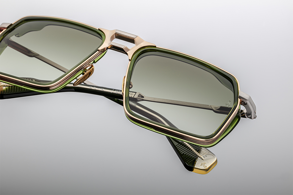 Close shot of the GT‑R Rover bridge: double‑bridge architecture with the upper gold bar and lower bar separated, green insert lining the top rim. Finish is polished gold with crisp joinery. Lens gradient fades from darker at top toward lighter bottom