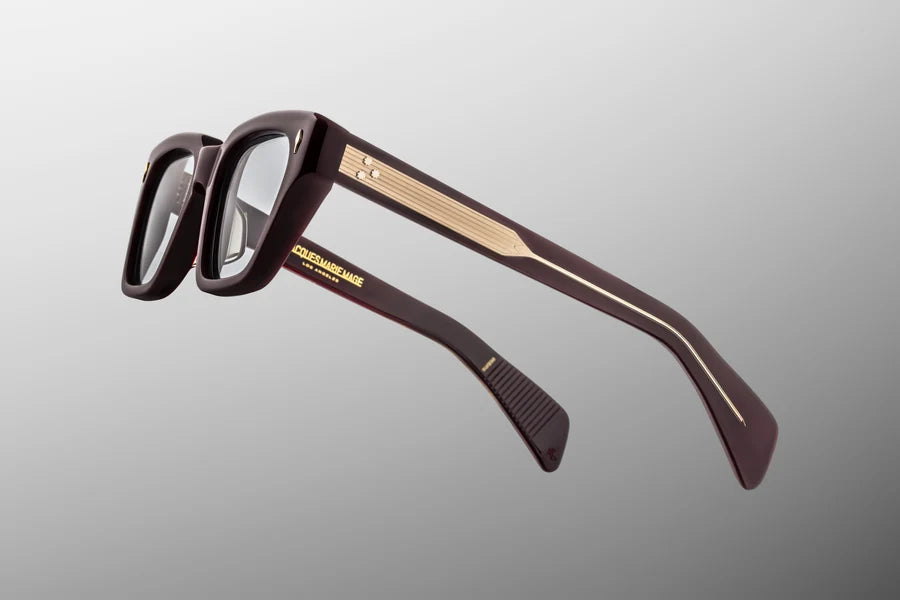 Side profile view of the Jacques Marie Mage Ichikawa in Wine. The focus is on the thick, custom double-laminated acetate temple arms. The outer layer features the deep wine red tone, which transitions into a crystal-clear inner layer. A premium, tension-secured sterling silver 7-barrel hinge firmly fastens the temple arm to the frame face. Available at WINK Optometrists.