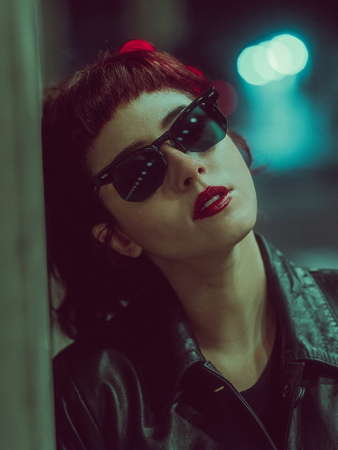 Model wearing Jacques Marie Mage Jean Titan eyeglasses — polished grey‑titan acetate semi‑rimless frame with strong brow-line, paired with light aqua lenses