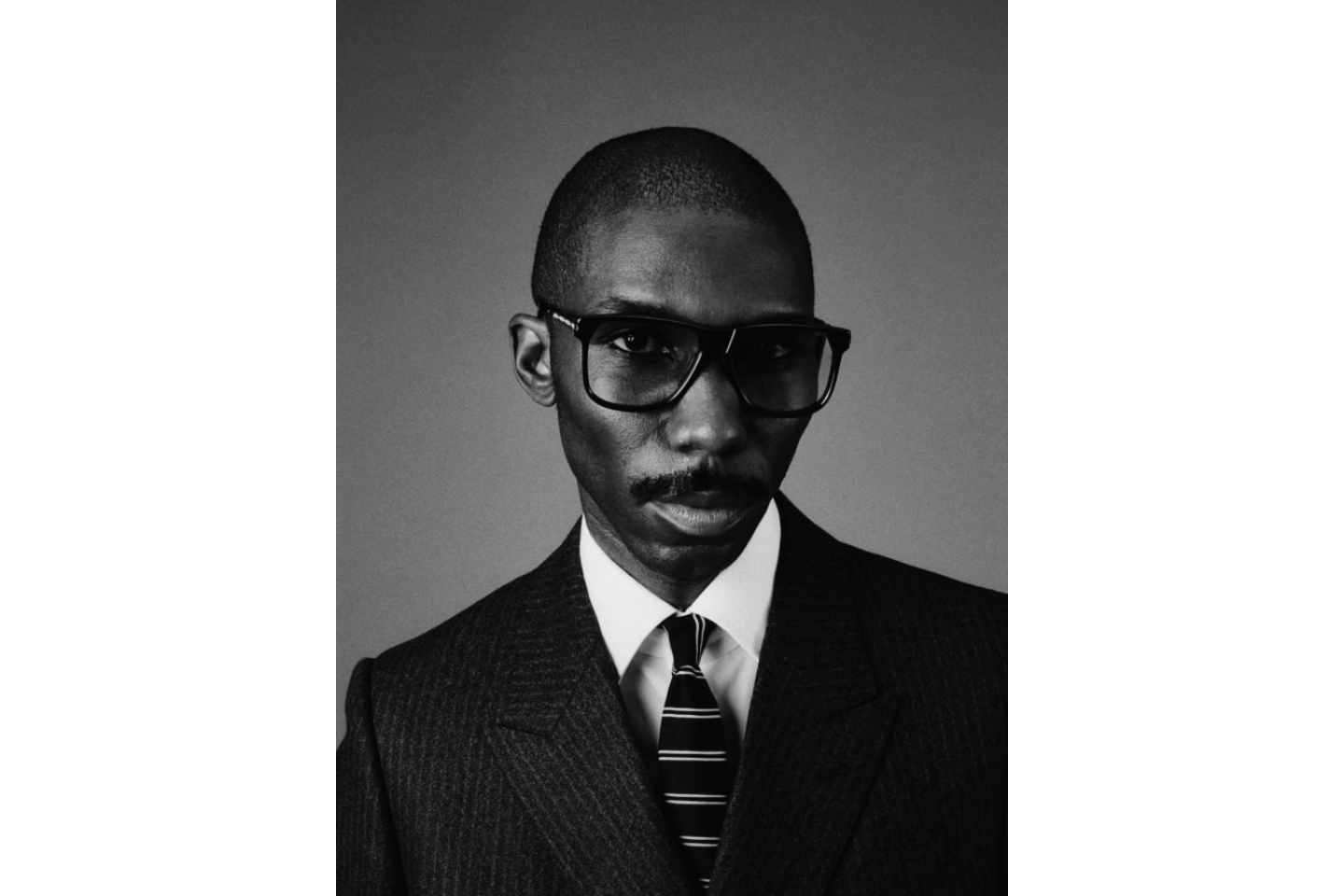 Model wearing the 70's inspired boxy Kirkland frame by Jacques Marie mage with warm Brown Cured Cellulose Acetate front and Light Brown lenses , 100% Beta titanium Light gold engraved temples. Light gold tension secured custom arrowhead mono block hinge. Available at WINK Optometrists