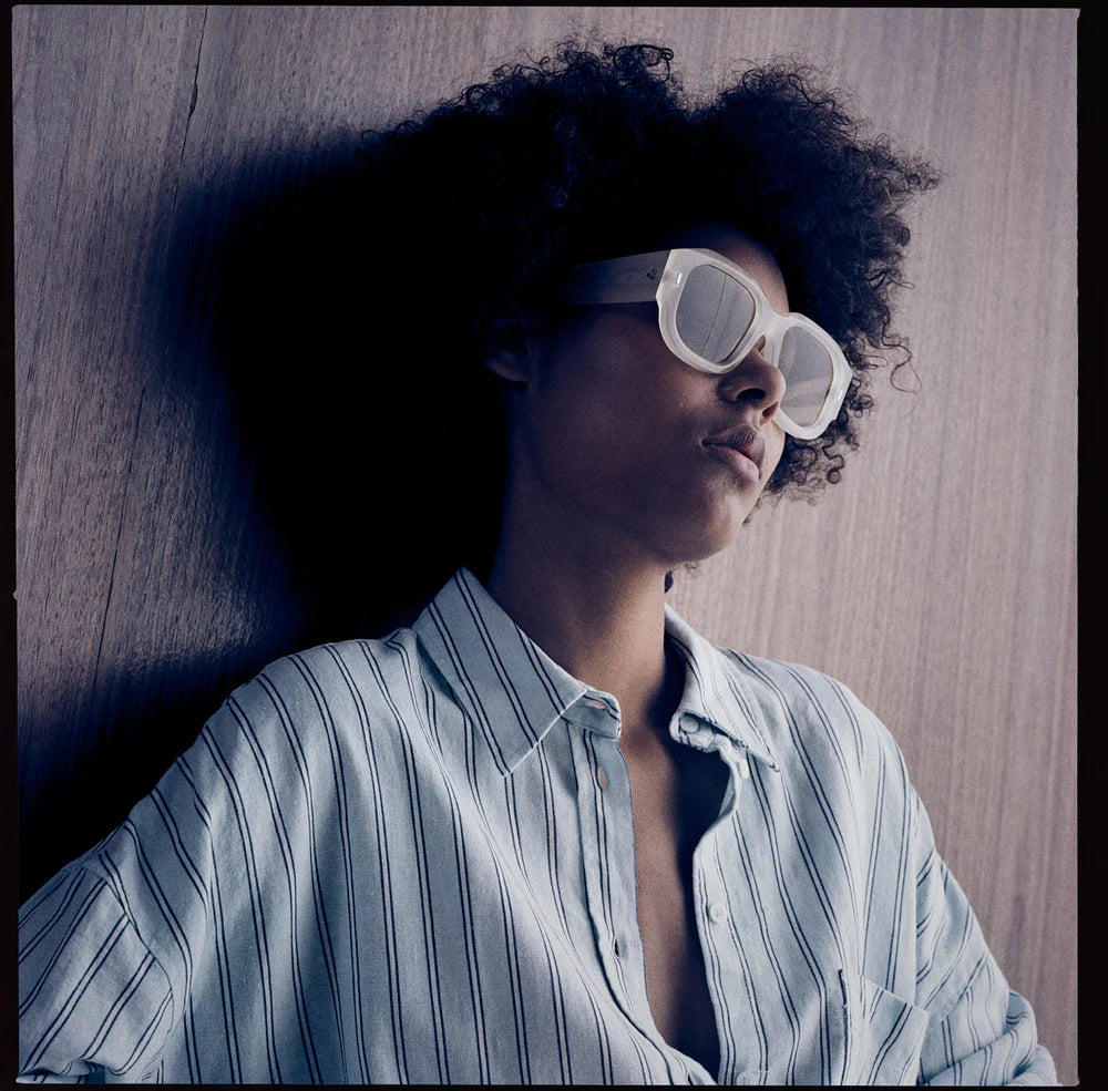 Model wearing Jacques Marie Mage Lacy dune sunglasses, showing oversized square shape and neutral sand tone