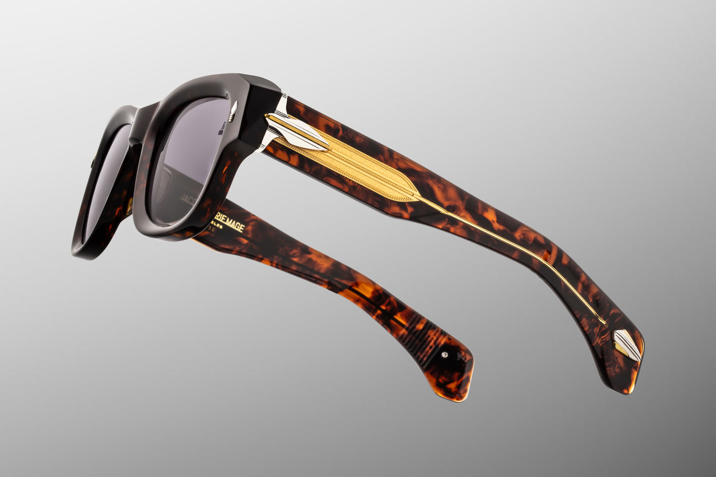 Side profile of JMM Conrad Beau sunglasses highlighting the ornate temples. The double-laminated temples feature a clear beige acetate exterior that leaves a custom-braided dark gold wirecore fully visible. Detailed silver palladium-plated arrowhead ornaments sit at the hinge assembly