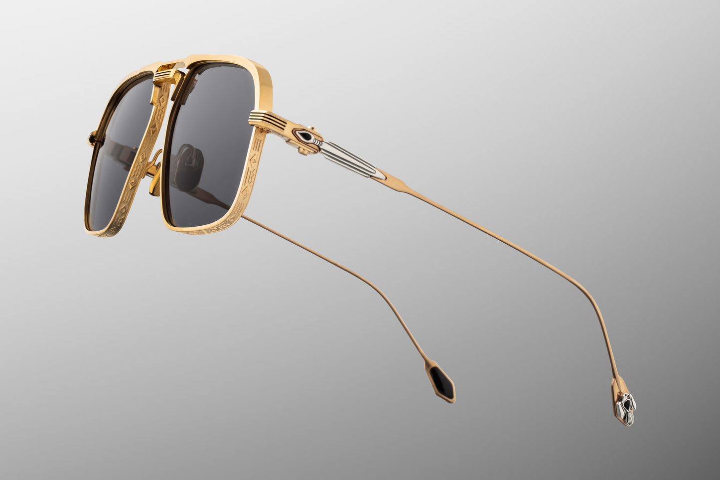Side profile of JMM Labarge Maxi sunglasses highlighting the detailed temples. The dark gold beta-titanium arms feature sculptural sterling silver arrowhead motifs inlaid with hand-shaped black onyx gemstones. The frames are secured with custom silver monoblock hinges.