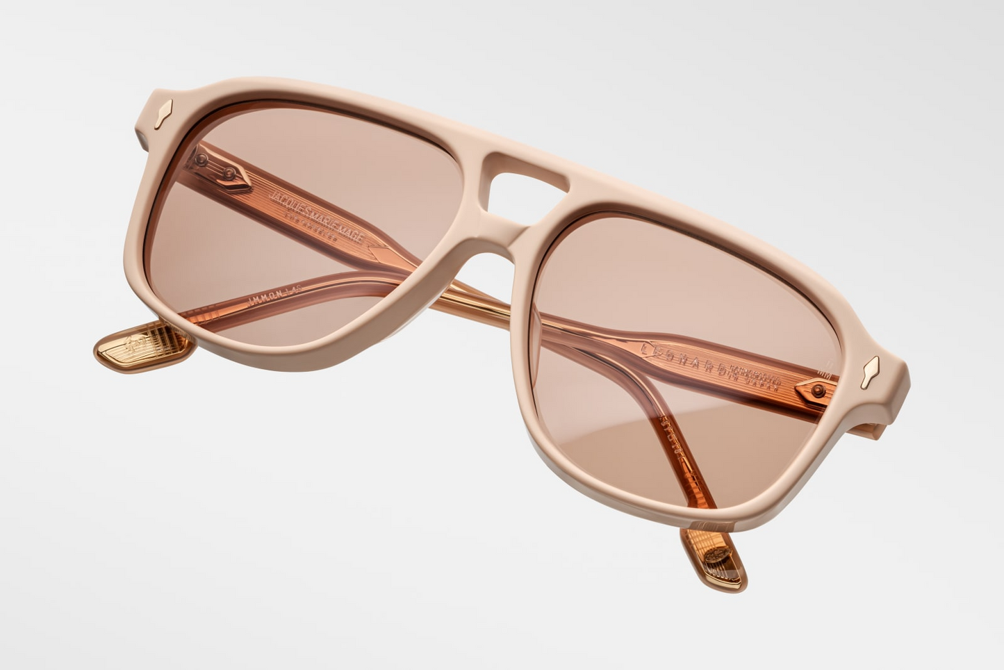 Three-quarter angled view of Jacques Marie Mage Leonard Suede sunglasses in Dust Suede: emphasizes the bold, rounded silhouette with a slight upward curve at the temples. The matte orange finish contrasts with the polished interior, highlighting the craftsmanship.
