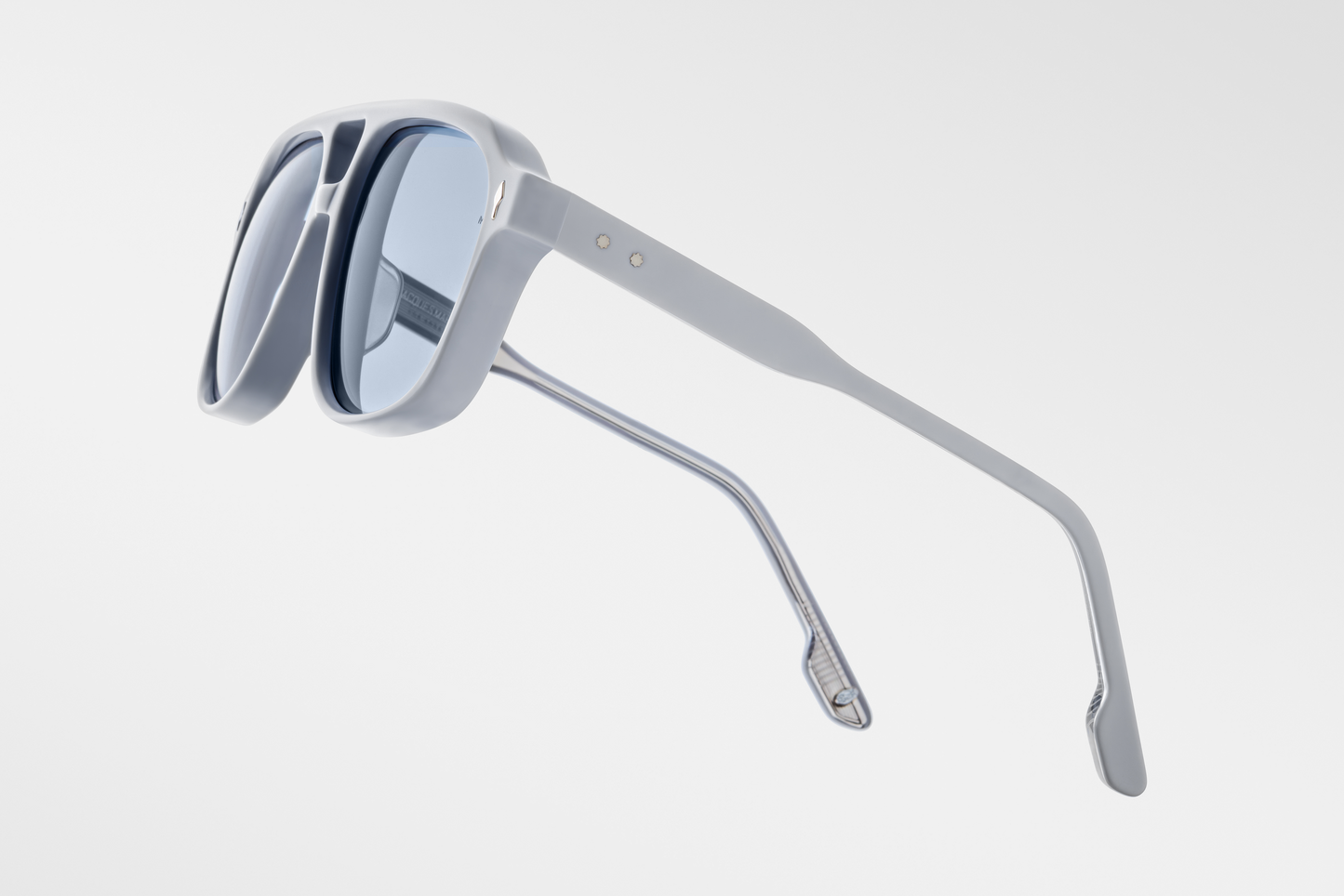 Three-quarter angled view of Jacques Marie Mage Leonard Suede sunglasses in Sky Suede: emphasizes the bold, rounded silhouette with a slight upward curve at the temples. The matte blue finish contrasts with the polished interior, highlighting the craftsmanship.