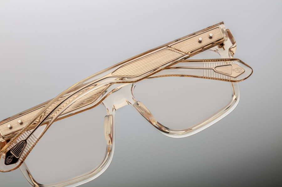 Detailed view of Jacques Marie Mage Lucknow Pearl glasses in translucent crystal-acetate. The temples reveal an embedded light-gold Art Deco wire core with precise engraving, secured by sterling silver arrowhead pins and tension secured 5 barrel hinges. The temple tip ends in a polished metal logo.
