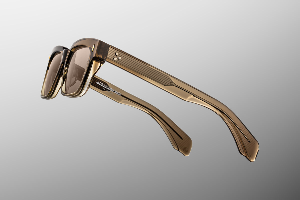 Macro shot of the temple arm on Jacques Marie Mage Molino Lescot sunglasses. The crystal-clear outer laminate layer provides a window to the exposed silver palladium wire core engraved with intricate Art Deco filigree.