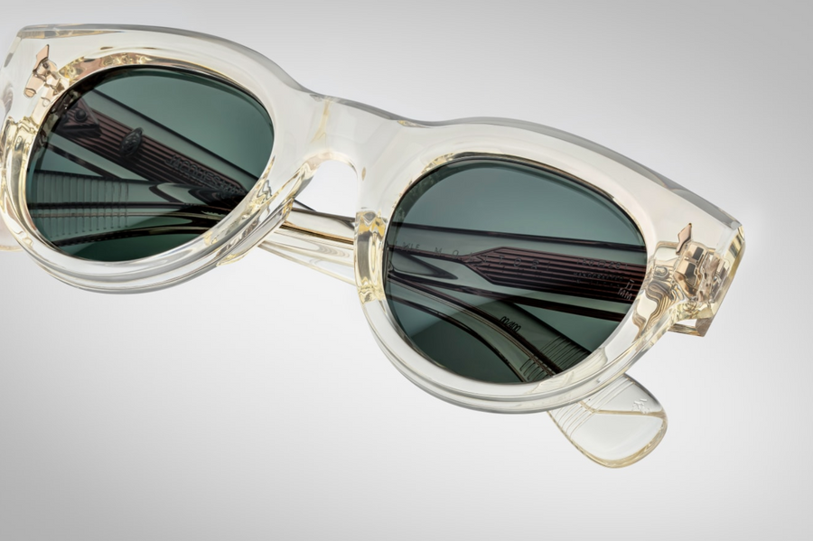An up-close view of the Molitor Brut Spruce sunglasses' lenses, showcasing the Spruce green CR39 lenses with backside anti-reflective coating. The lenses are 6-base, providing full UV protection. The frame is constructed from 10mm polished cured cellulose acetate, ensuring durability and a premium feel.