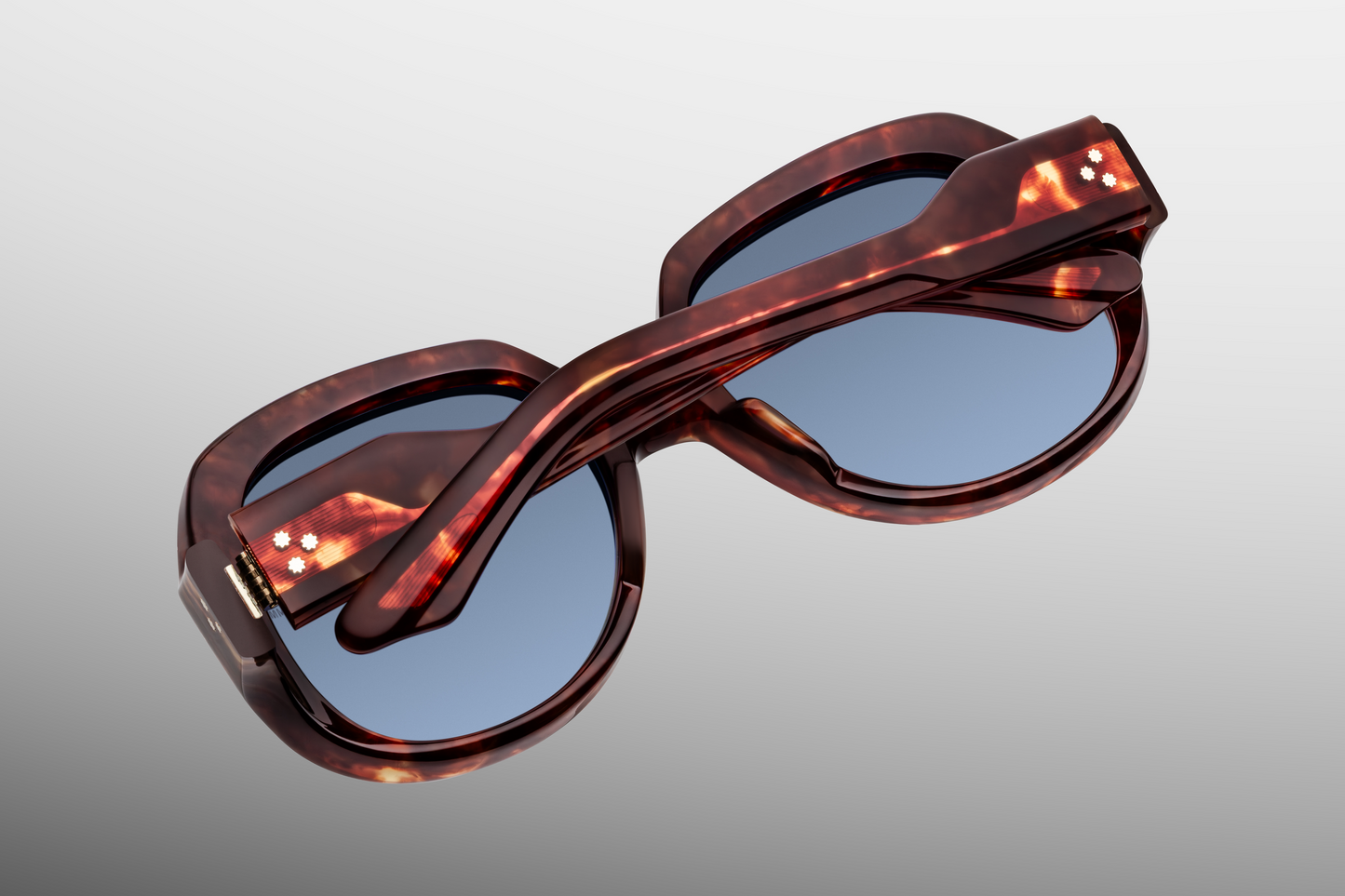 Interior of Ocean Child Breccia — gradient denim Armorlite lenses framed by rich red-havana breccia acetate, with inner‑temple JMM hallmarks