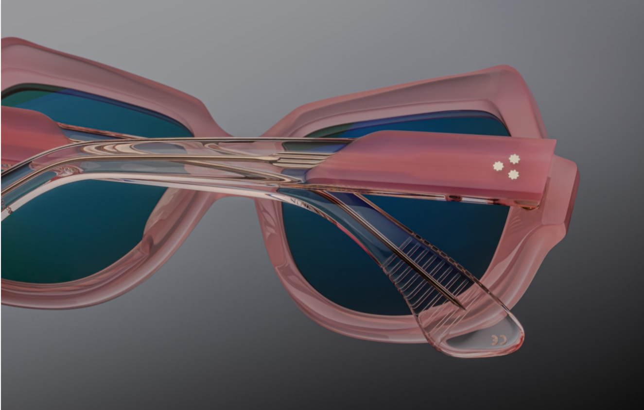 Backside view of the temple: layered pastel pink acetate is visible in cross-section behind the hinge, revealing the internal light‑gold wire‑core. The recessed hinge is secured with matching gold rivets. The temple underside is embossed with ‘54–18–142’, limited‑edition serial number, and ‘Handmade in Japan’ in silver foil.