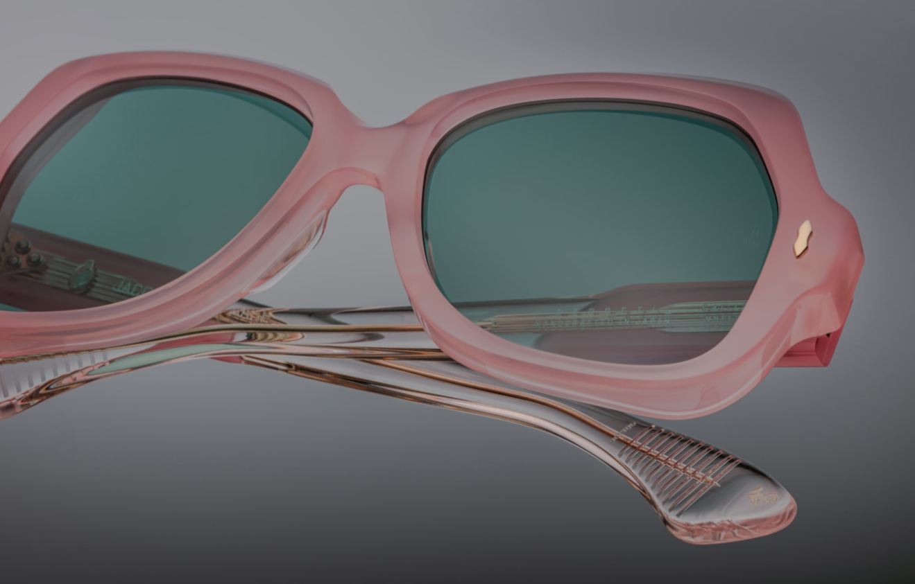 Close-up frontal detail capturing the saddle keyhole bridge and right lens: the clear round CR‑39 demo lens sits precisely within the pink acetate rim. The polished bevel edge highlights high craftsmanship, and one of the light‑gold arrowhead pins is visible at the rim’s corner