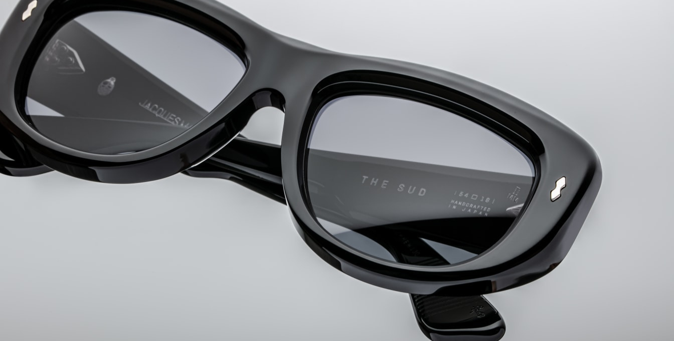 Rivet details for Jacques Marie Mage The Sud | Francoise sunglasses from the Erin Wasson for JMM collection. The sculptural, softly sloped square frame is crafted from 10 mm polished black acetate. It features double-acetate temples enclosing a hidden cantilever silver wire-core, accented with sterling silver double-arrowhead hinge pins, spur-shaped rivets, and Marseille crest temple tips. The lenses are deep jet-gradient CR39 with backside anti-reflective coating and 100%UV protection.