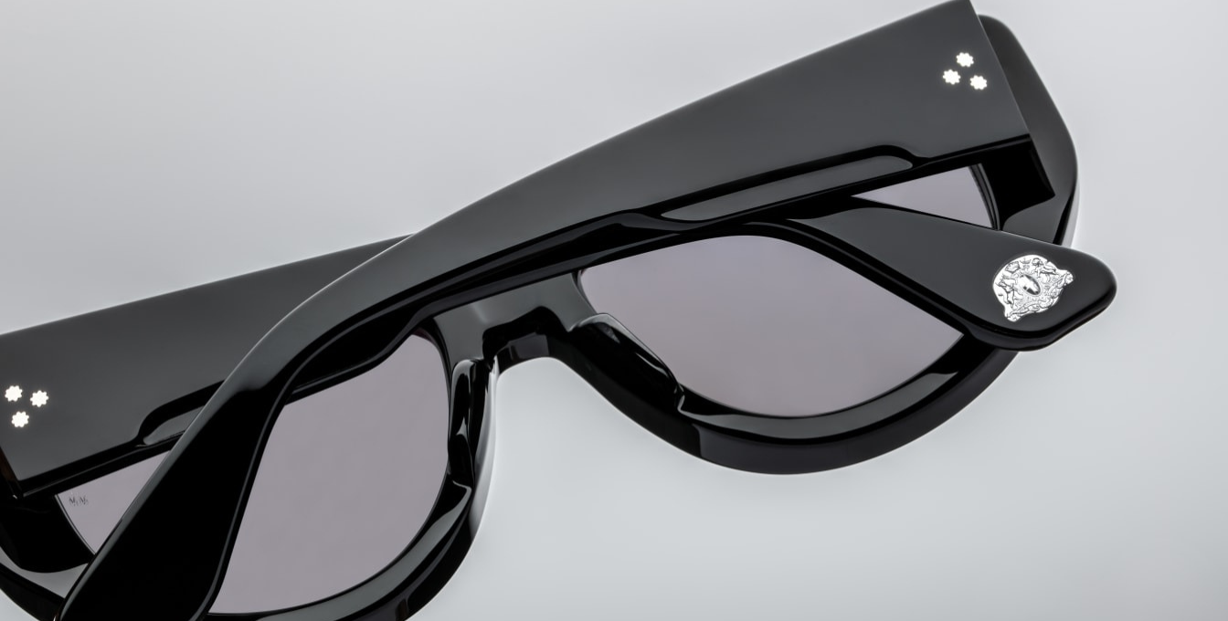 Jacques Marie Mage The Sud | Francoise sunglasses from the Erin Wasson x JMM collection. The 10 mm black acetate temple sweeps backward, housing a hidden cantilever silver wire-core within its double-laminated structure. At the end of each temple, a polished silver emblem—the Crest of Marseille—is inlaid, mirroring the double-arrowhead hinge pins and spur-shaped rivets nearby. Handcrafted in Japan, these limited-edition tourers (500 pcs) pair luxurious detailing