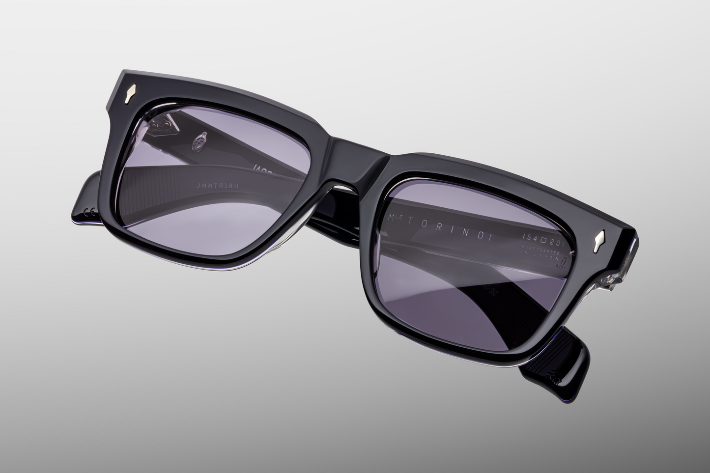 Close-up front detail of Jacques Marie Mage Fellini Hudson sunglasses showing deep blue acetate frame and signature sterling-silver arrowhead pins.
