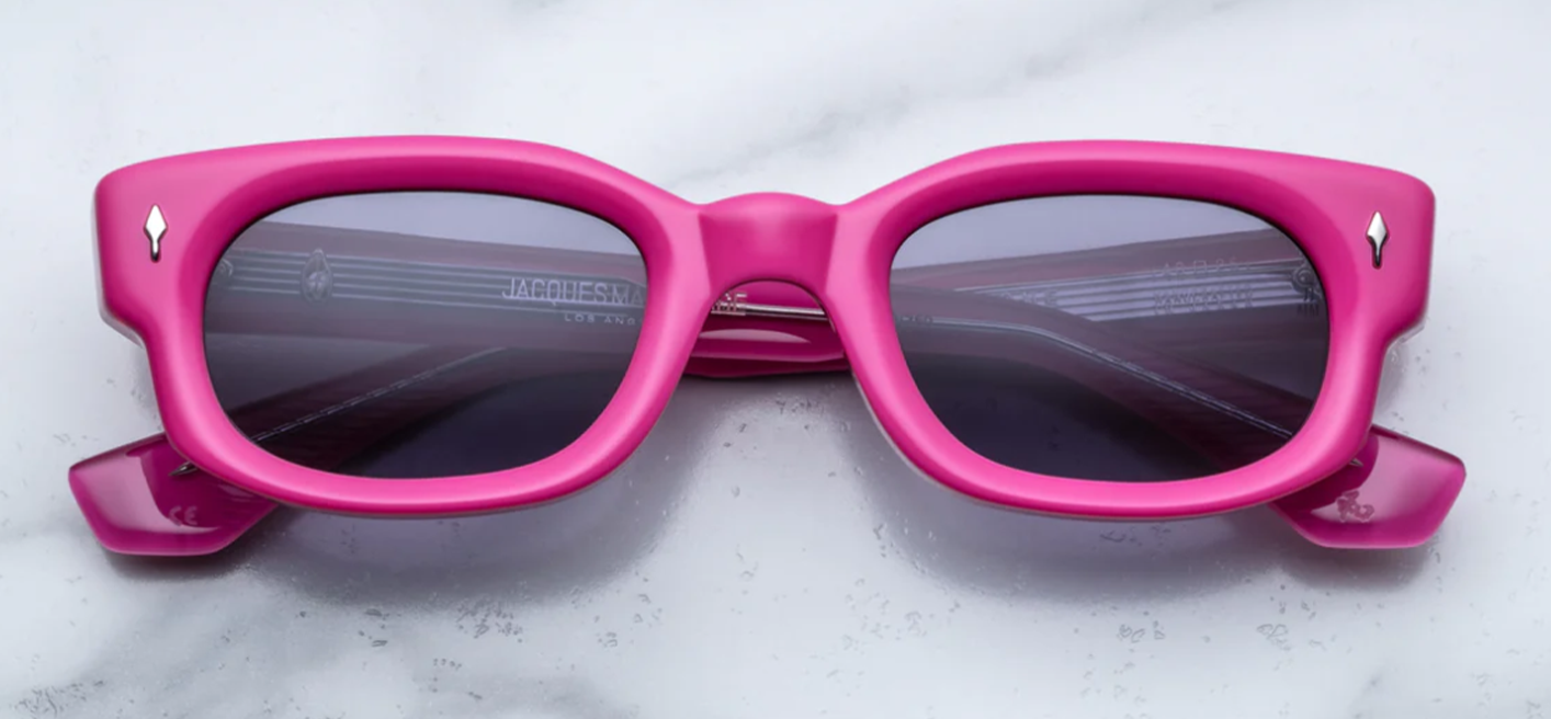 Straight-on view of Jacques Marie Mage Whiskeyclone sunglasses in vibrant Azalea Pink acetate. The medium rectangular frame has a full-rim construction with soft rounded edges and a pronounced saddle bridge. The bright pink acetate features subtle translucency, complemented by silver arrowhead pins embedded at the upper corner