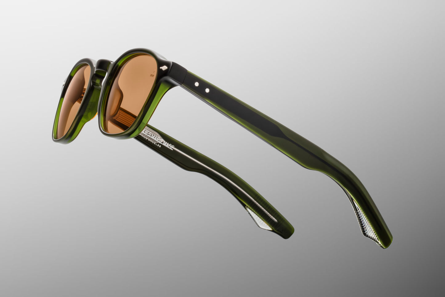 Side view of the JMM Zephirin Borneo sunglasses temple arm, showcasing the glossy green double-laminated acetate construction and the signature flush sterling silver spur-shaped rivets.