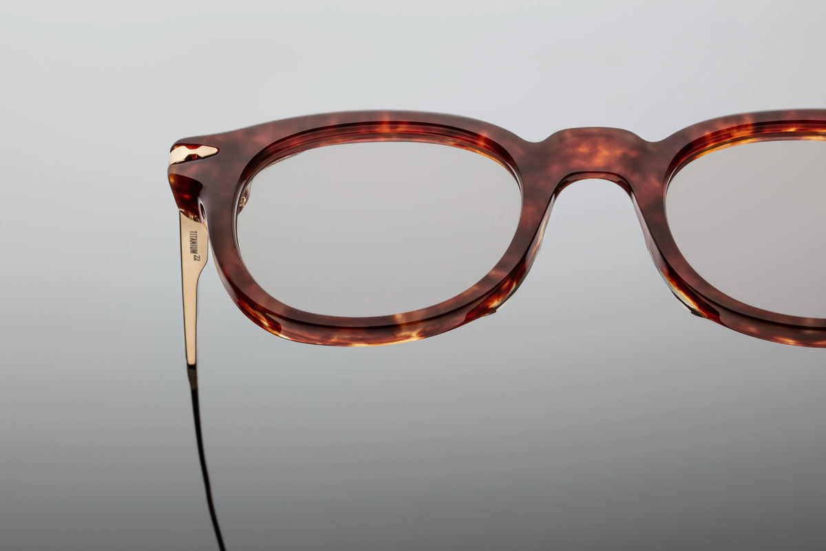 A macro close-up of the Jacques Marie Mage Hisao Breccia hinge mechanism, showcasing the luxury craftsmanship available at Wink Optometrists. The shot captures the gold tension-secured hinge and intricate engravings on the titanium temple.