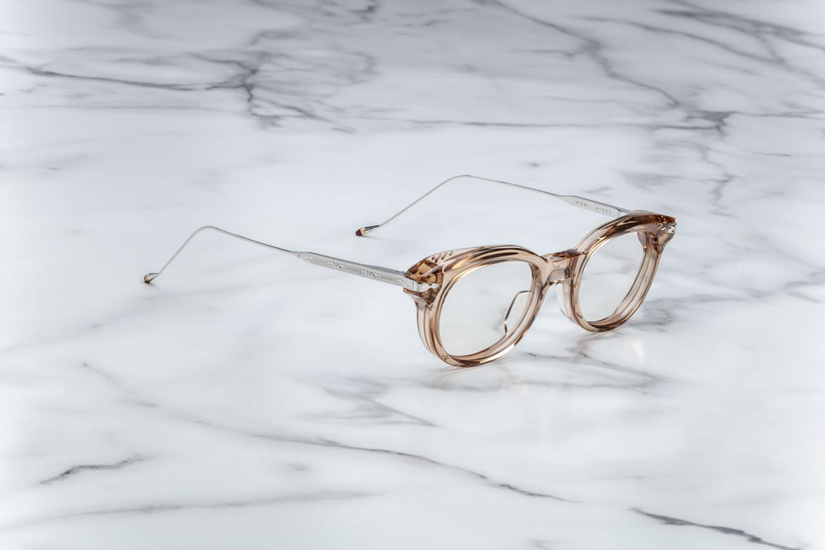 Side profile of the Jacques Marie Mage Hisao Sand glasses from Wink Optometrists. The light tan acetate front meets silver palladium beta titanium temples decorated with finely engraved custom Native iconography