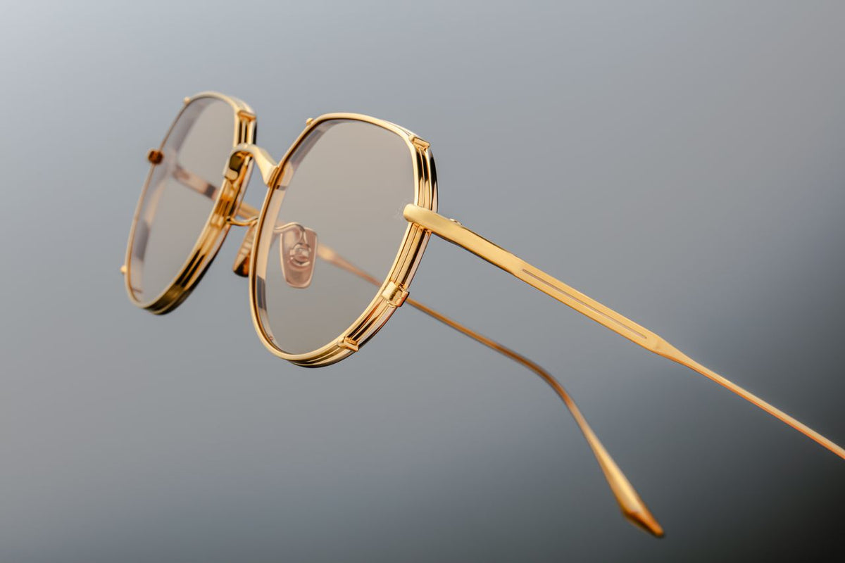 Close-up detail of the minimalist temple tips on the Jacques Marie Mage Hartana Gold sunglasses from Wink Optometrists. The fine gold beta titanium arms terminate in a solid, cleanly sculpted metal point with subtle structural grooving.