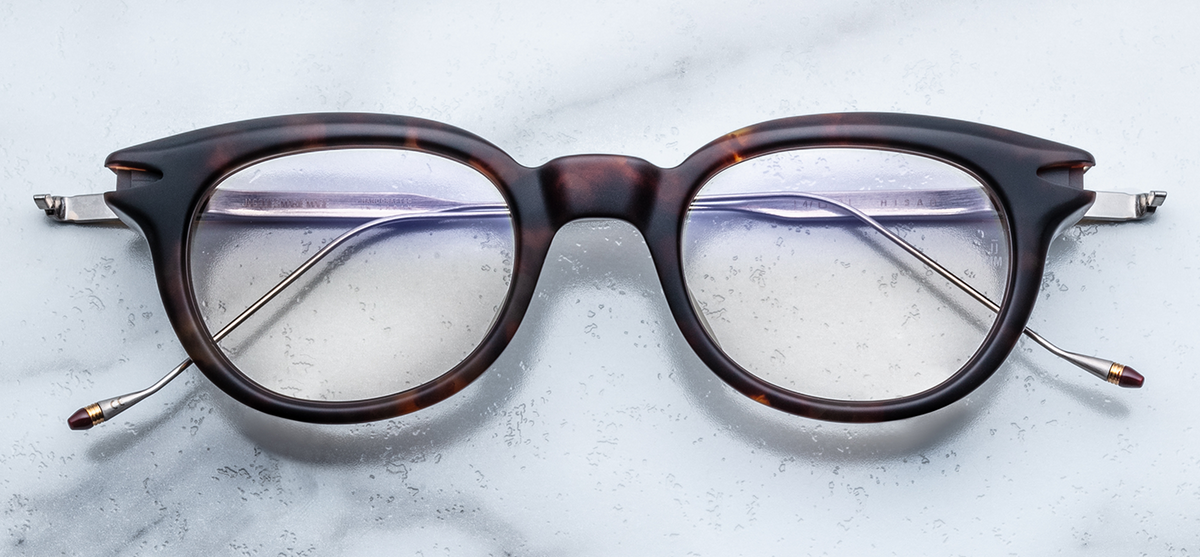 Front view of the Jacques Marie Mage Hisao RX eyeglasses in Havana. The frame features a bold, thick 10mm block of dark brown tortoiseshell acetate with a rectangular silhouette and structural beveling. Distinctive silver signature arrowhead front pins are visible on the outer corners, and the frame is fitted with clear optical demonstration lenses.
