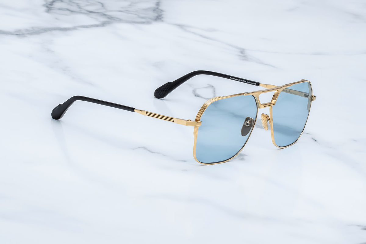 Full side profile of the Jacques Marie Mage 1980 Ciel sunglasses. Shows the ultra-thin, architectural moon gold titanium temple arms running back to seamlessly merge with polished black cured cellulose acetate temple sleeves. The number "1980" is finely engraved along the metallic arm. WINK Optometrists