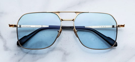 Front view of Jacques Marie Mage Stanley Kubrick 1980 sunglasses in Ciel. Features an oversized, lightweight aviator frame made of 100% beta titanium finished in brilliant moon gold. Includes a distinctive double nose bridge accented with fine black epoxy lines and fitted with striking, light-filled serene blue Armorlite lenses. WINK Optometrists