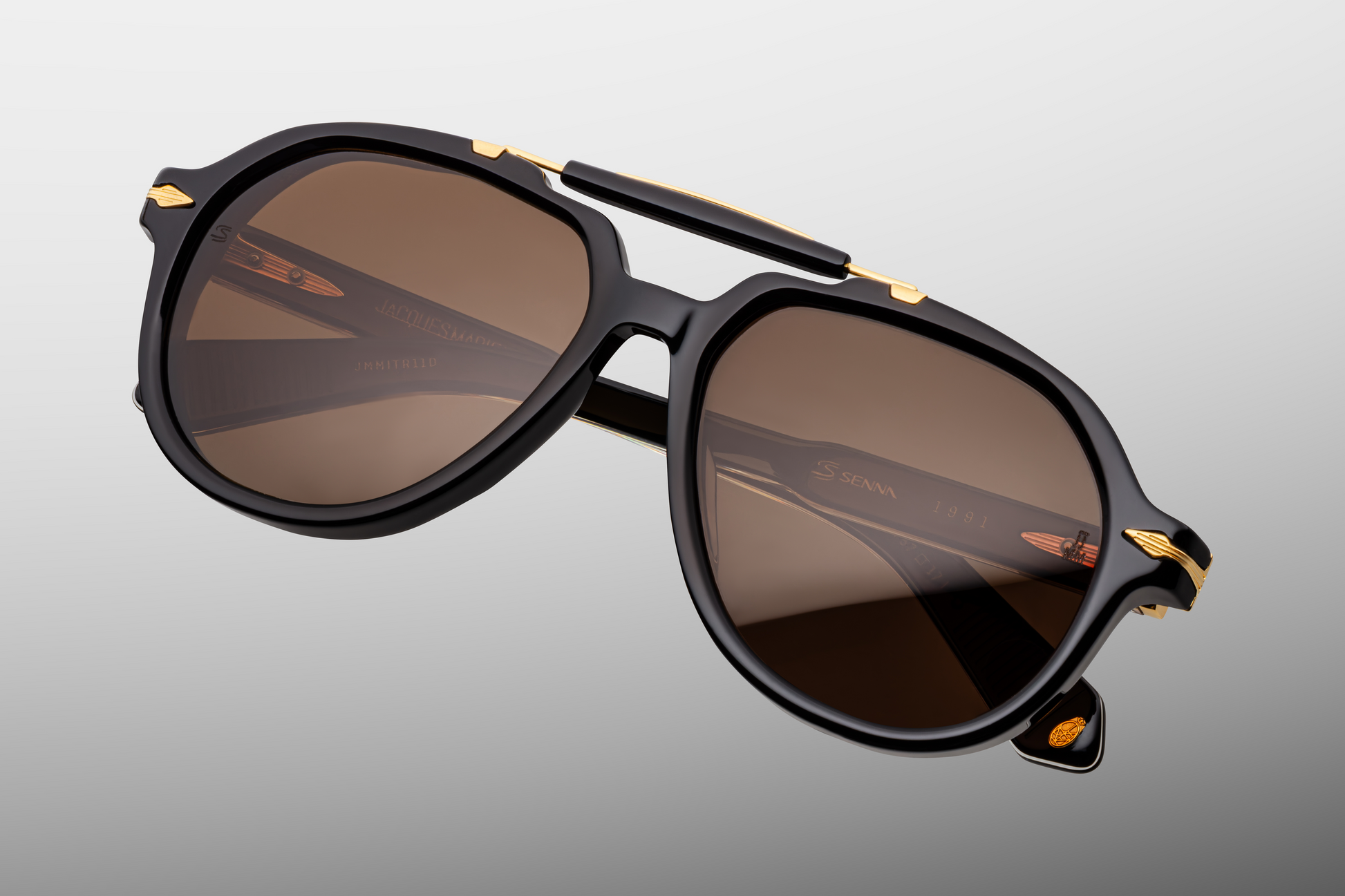 Close-up of the front of Jacques Marie Mage 1991 Eclipse 2 sunglasses highlighting the metal arrowhead pin, sculpted top-bar, nose pads and rich hazel crown-mineral lenses, available at WINK Optometrists