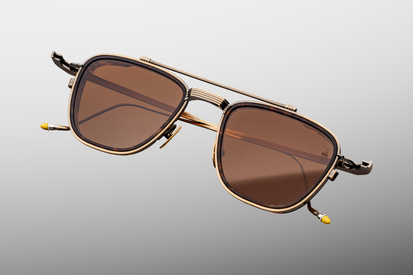 Close-up of front of Jacques Marie Mage Ayrton Senna 1992 Antique Gold sunglasses highlighting the sculptural top-bar, coined-edge beta-titanium eyerims, polished gold nose pads and pecan-brown crown-mineral lenses, available at WINK Optometrists