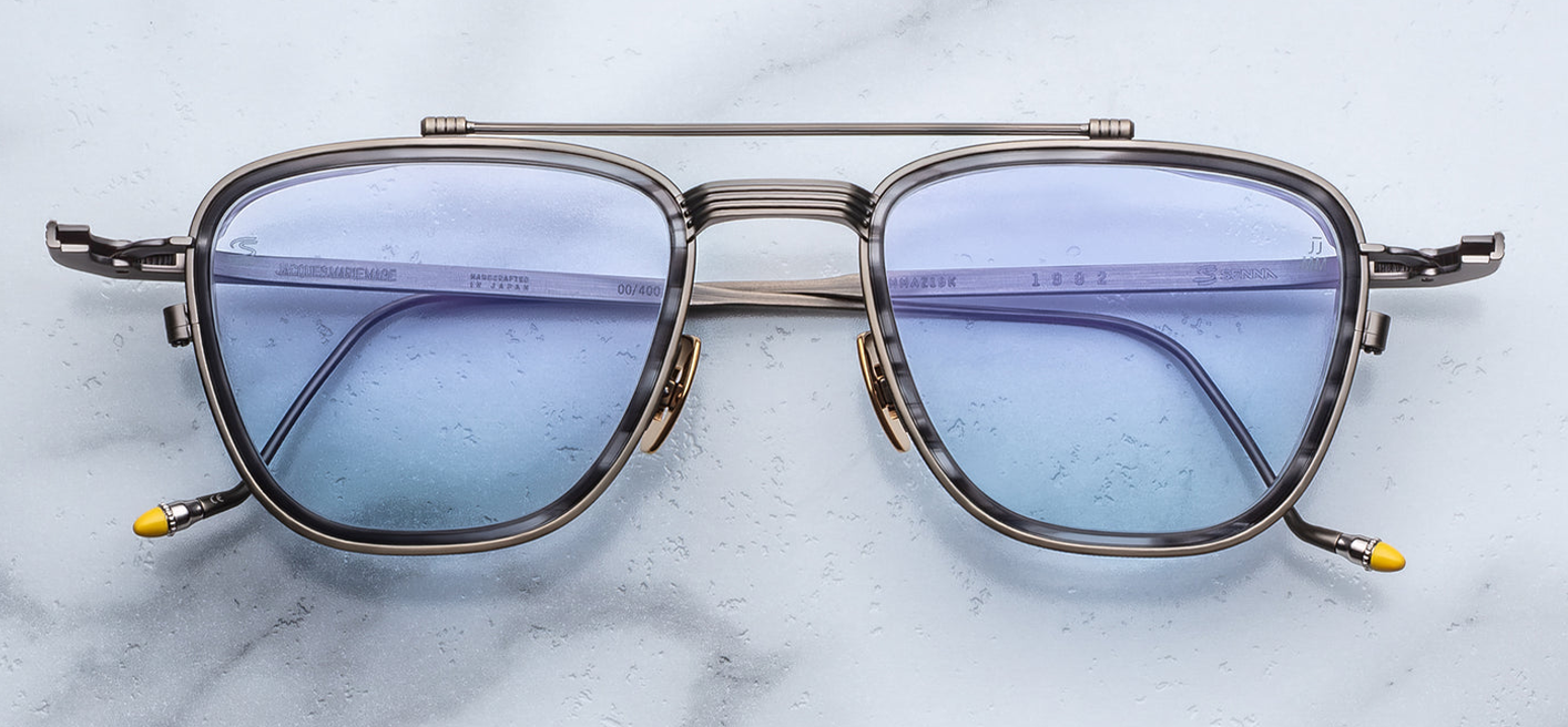 Front view of Jacques Marie Mage Ayrton Senna 1992 Antique Gunmetal sunglasses in matte gunmetal beta-titanium frame with 6 mm matte black/grey acetate lens-rim inserts and light blue crown mineral glass lenses, available at WINK Optometrists