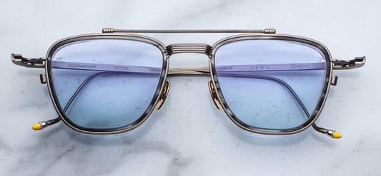 Front view of Jacques Marie Mage Ayrton Senna 1992 Antique Gunmetal sunglasses in matte gunmetal beta-titanium frame with 6 mm matte black/grey acetate lens-rim inserts and light blue crown mineral glass lenses, available at WINK Optometrists