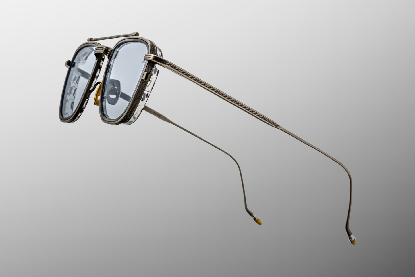 Detailed side close-up of Jacques Marie Mage Ayrton Senna 1992 Antique Gunmetal sunglasses showing monoblock hinge with refined hair-line engraving, beta-titanium temple core and hand-painted yellow temple tip, available at WINK Optometrists