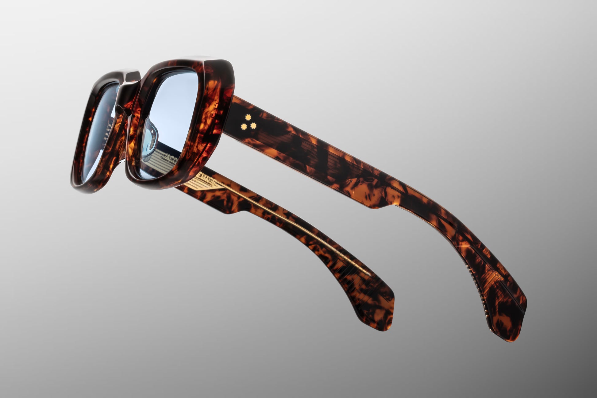 Side view of the JMM Aldo sunglasses temple arm, showcasing the glossy Havana tortoise exterior, clear beige inner laminate, 10k gold spur rivets, and the custom dark gold wirecore running through the temple
