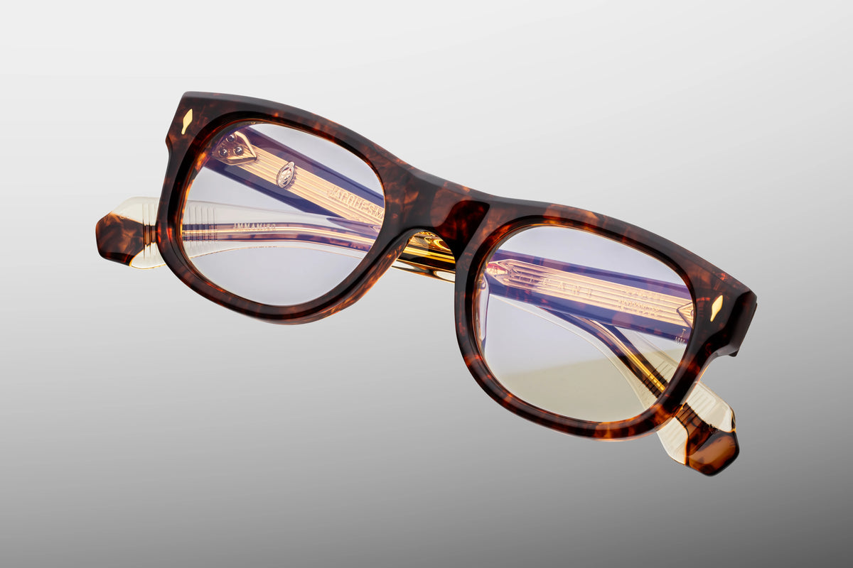  Top-down view of the Jacques Marie Mage Amilcar RX Argyle eyeglasses, showing the heavy 10mm thickness of the front block acetate and the perfectly balanced alignment of the frame profile. From above, the clear beige inner laminates on the temples showcase the full length of the engraved dark gold wire cores and the robust, multi-barrel hinge construction. Available at WINK Optometrists.