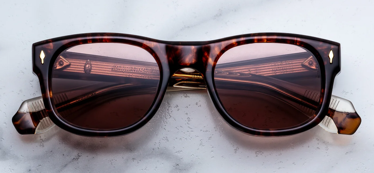 Front view of Jacques Marie Mage Amilcar sunglasses in Argyle Havana tortoise shell acetate, showcasing classic round lenses with a softly arched brow line, bronze lenses, and signature 18k dark gold arrowhead front pins