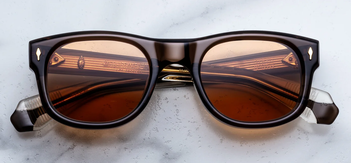 Front view of Jacques Marie Mage Amilcar sunglasses in London brown acetate, showcasing classic round lenses with a softly arched brow line, vivid orange lenses, and signature 18k dark gold arrowhead front pins.